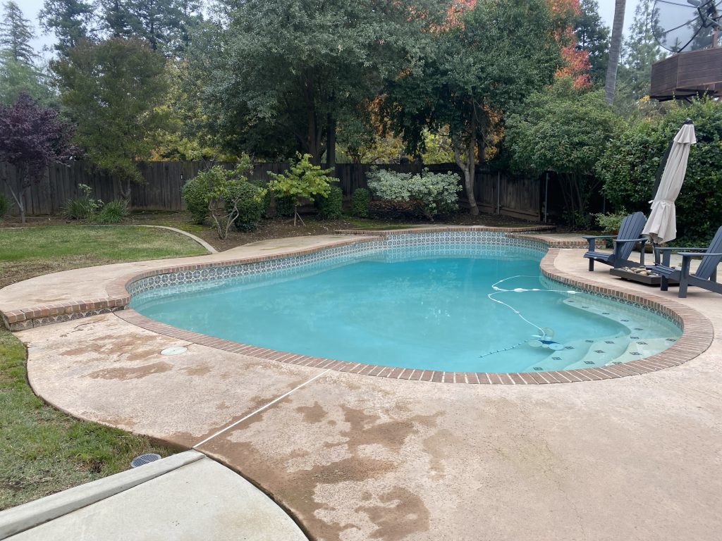 Before photo of the Wiedemeier backyard showing the existing pool deck and drainage conditions in Fresno, California.