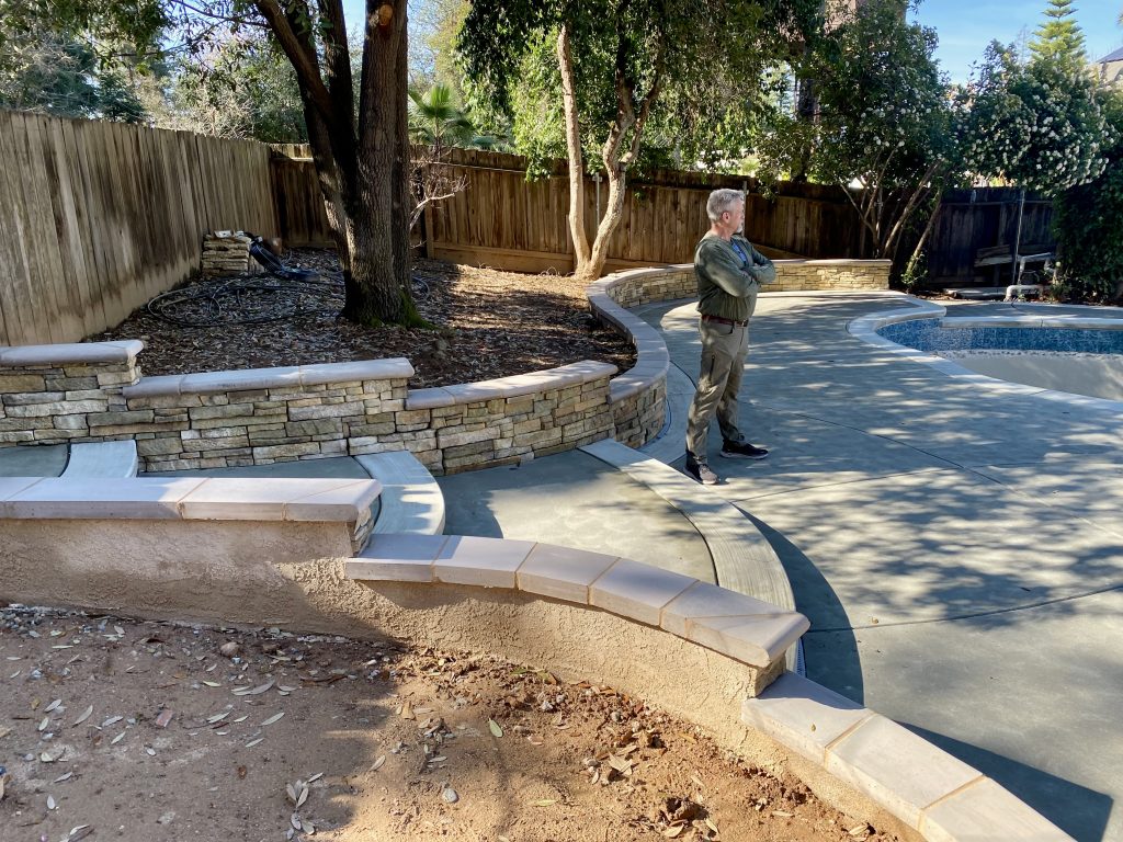 Homeowner Gary Wedemeyer reviewing the progress of construction as the new outdoor living space begins to take shape during the Wedemeyer backyard renovation.