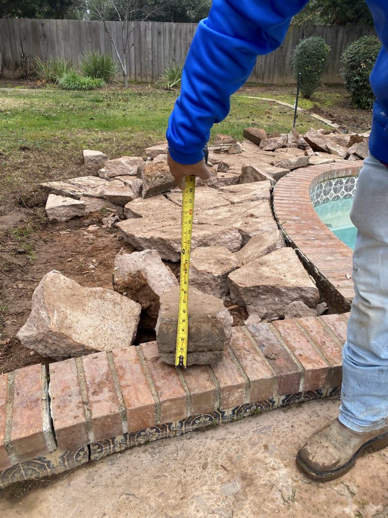 The existing pool deck is removed to prepare for grading, drainage improvements, retaining wall construction, and an expanded outdoor living space.