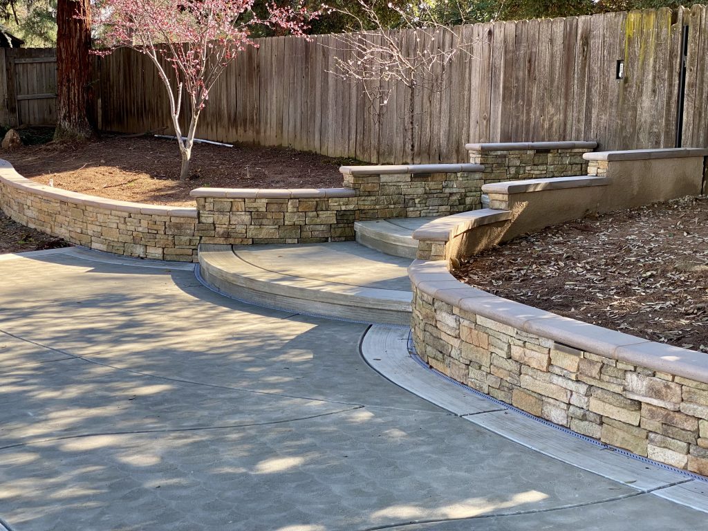 Completed retaining wall and architectural stairway leading to the neighborhood bike path, faithfully constructed from the original design sketch during the Wedemeyer backyard renovation by Sunset Construction.
