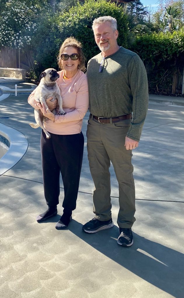 Gary and Carey Wedemeyer with their pug enjoying their completed backyard following the Sunset Construction outdoor living renovation in Fresno, California.